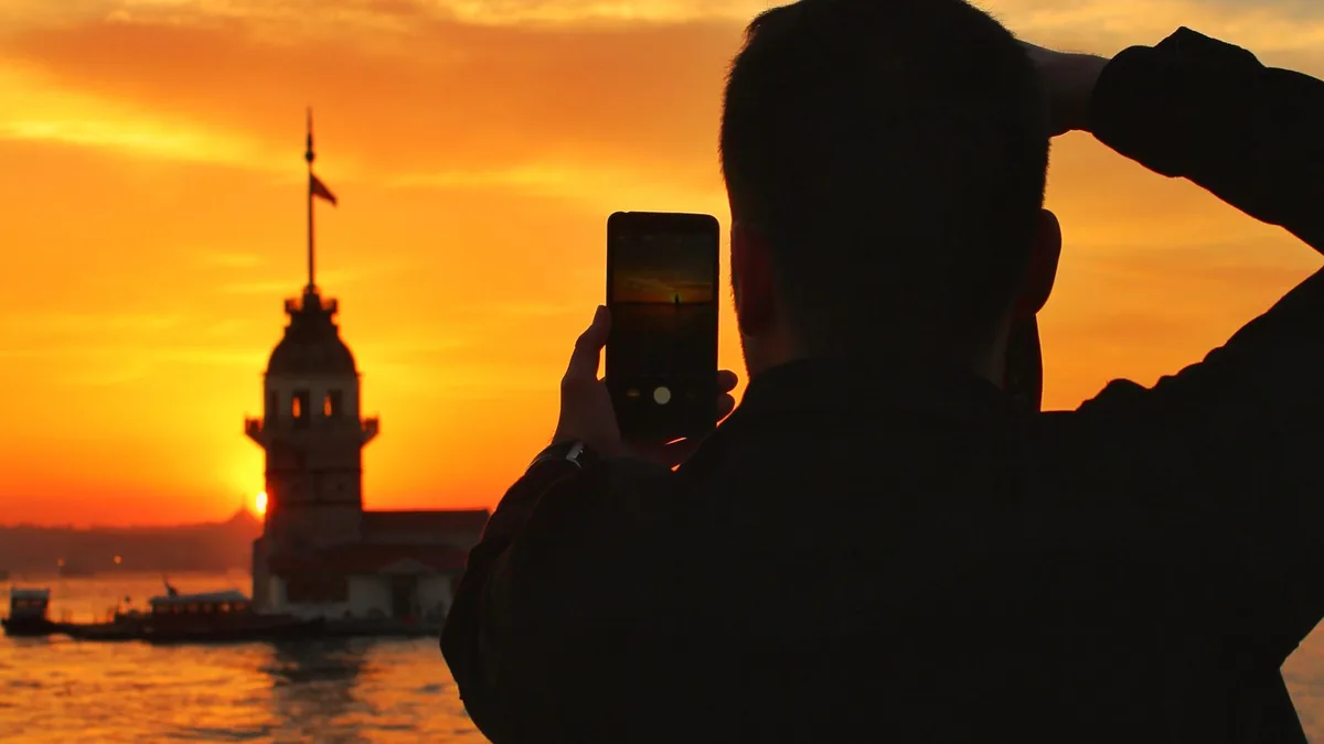 Gün batımında telefonla güneşin fotoğrafını çekmek